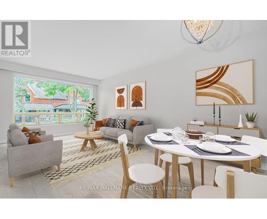 A modern dining room with a white table and chairs, a grey sofa, and a large window with a view of a house.