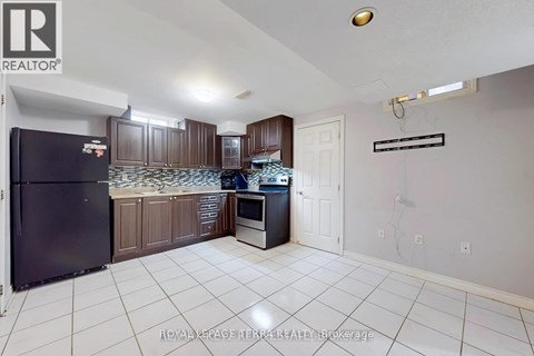 A kitchen with a black fridge and a white tiled floor.