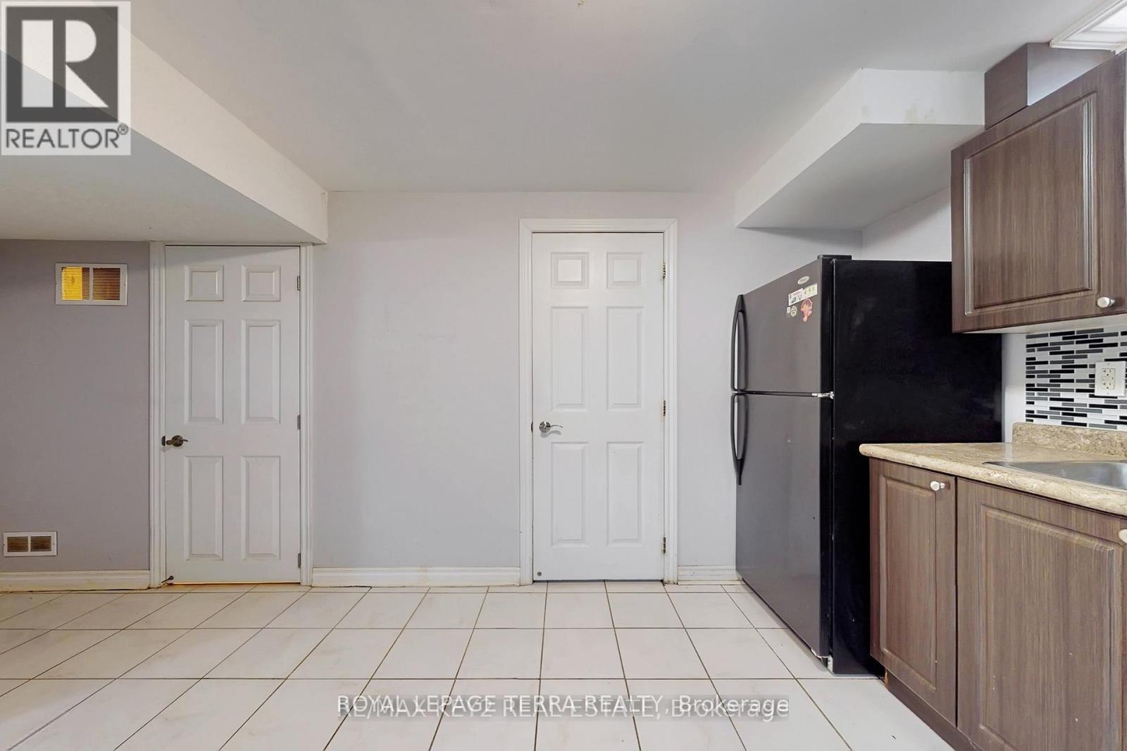 A kitchen with a black fridge and white doors.