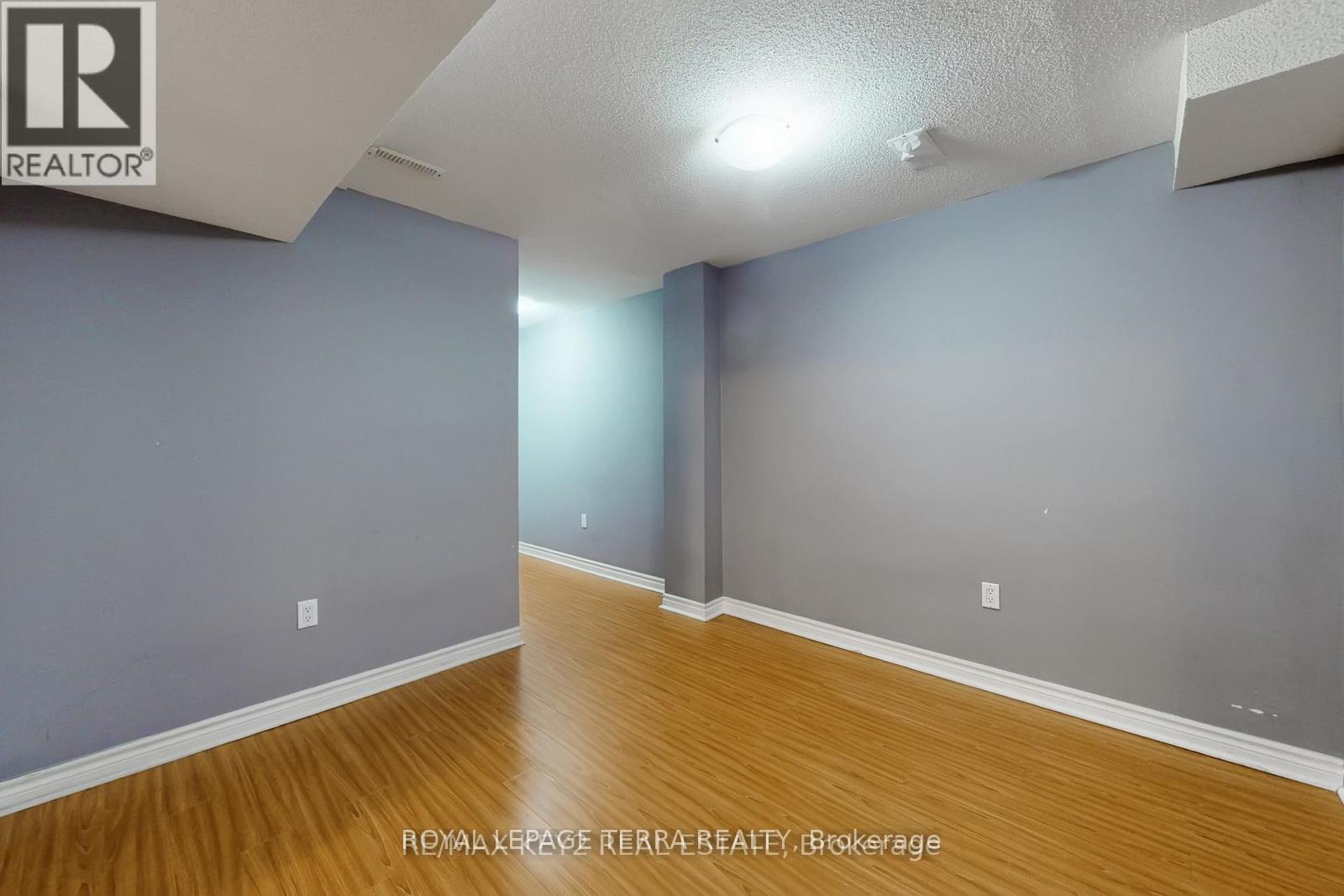 A room with wooden flooring and a grey wall.