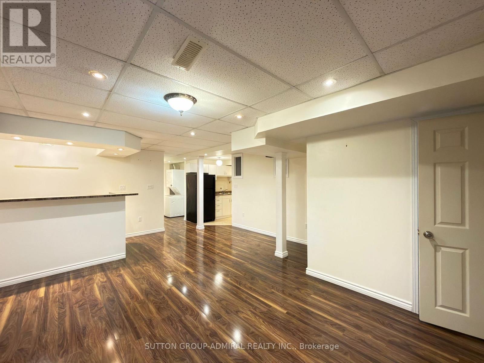 A room with wooden floors and white walls, with a door on the right side.