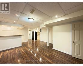 A room with wooden floors and white walls, with a door on the right side.