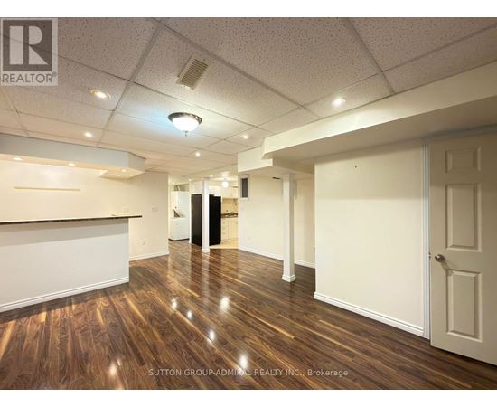 A room with wooden floors and white walls, with a door on the right side.