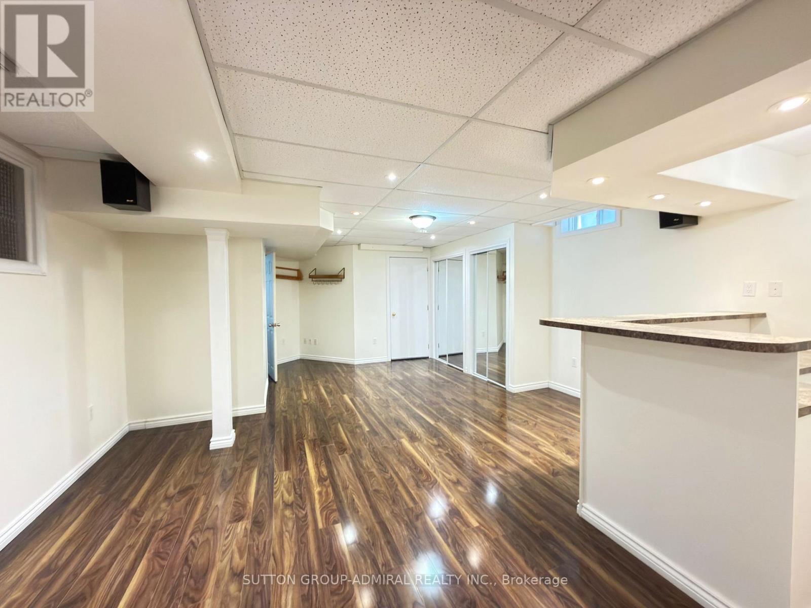 A spacious room with wooden flooring and white walls, likely a commercial space.