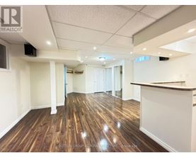 A spacious room with wooden flooring and white walls, likely a commercial space.
