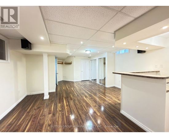 A spacious room with wooden flooring and white walls, likely a commercial space.
