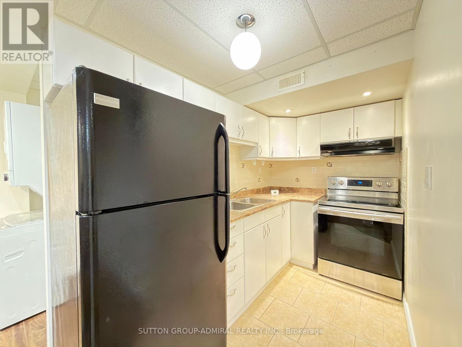 A black fridge in a kitchen with white cabinets.