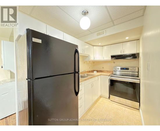 A black fridge in a kitchen with white cabinets.