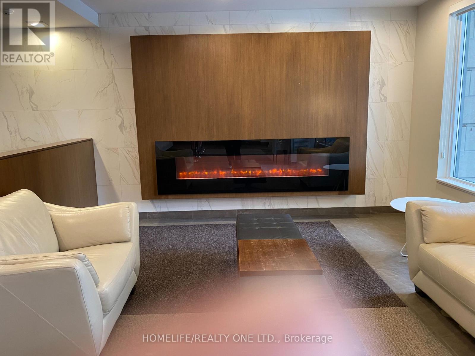 A modern living room with a fireplace and two white sofas.