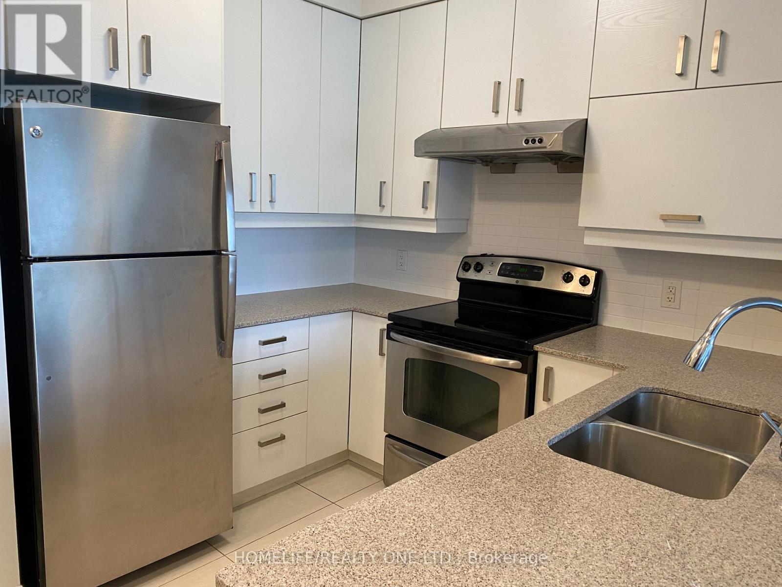 A kitchen with a stainless steel refrigerator and white cabinets.