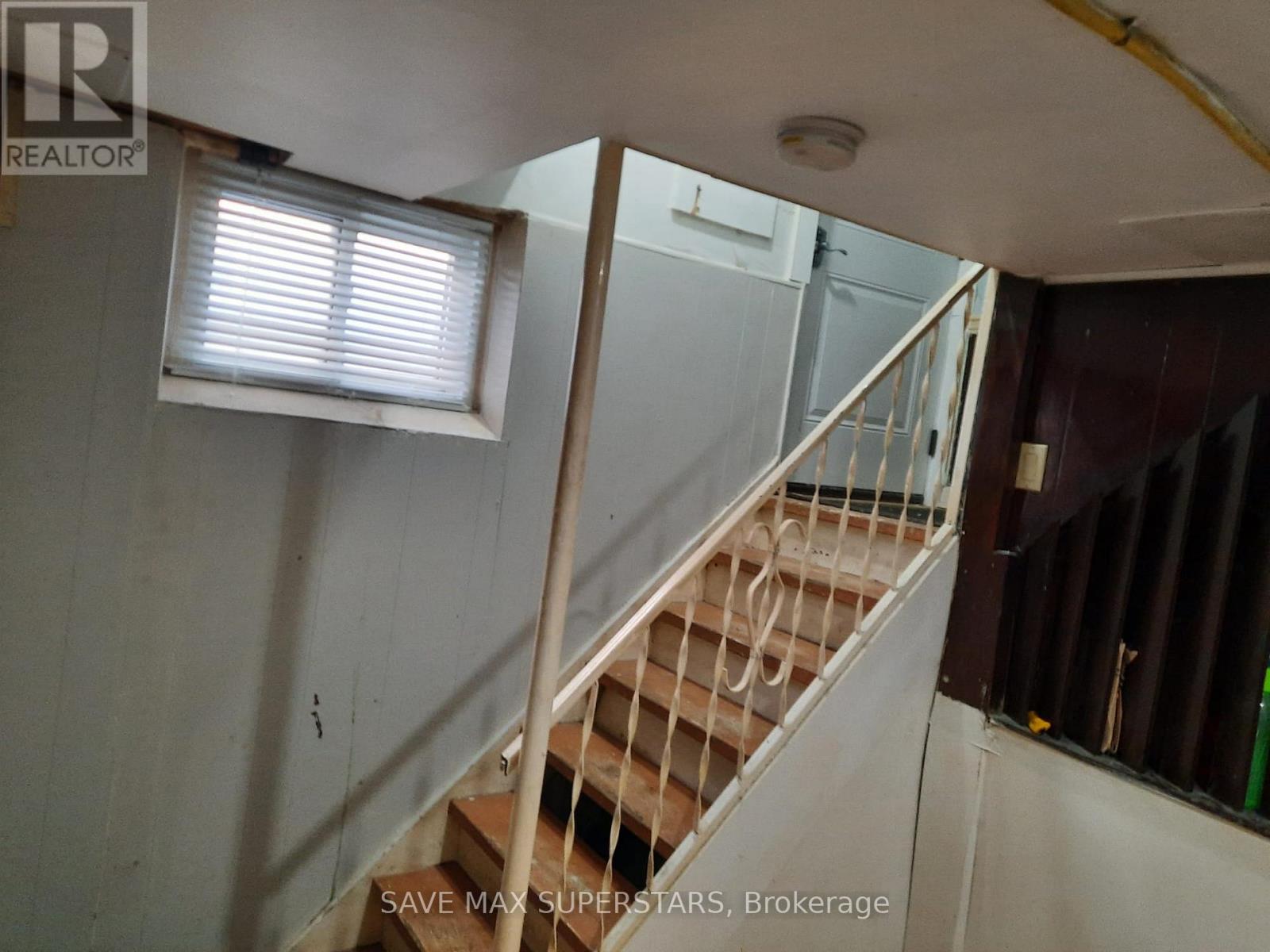 A staircase in a room with a window and a sign that says "SAVE MAX SUPERSTARS, Brokerage".