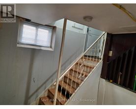 A staircase in a room with a window and a sign that says "SAVE MAX SUPERSTARS, Brokerage".