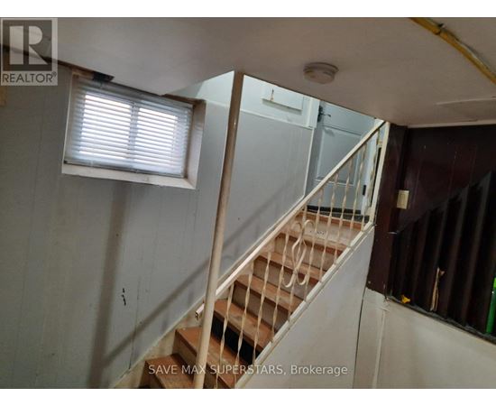A staircase in a room with a window and a sign that says "SAVE MAX SUPERSTARS, Brokerage".