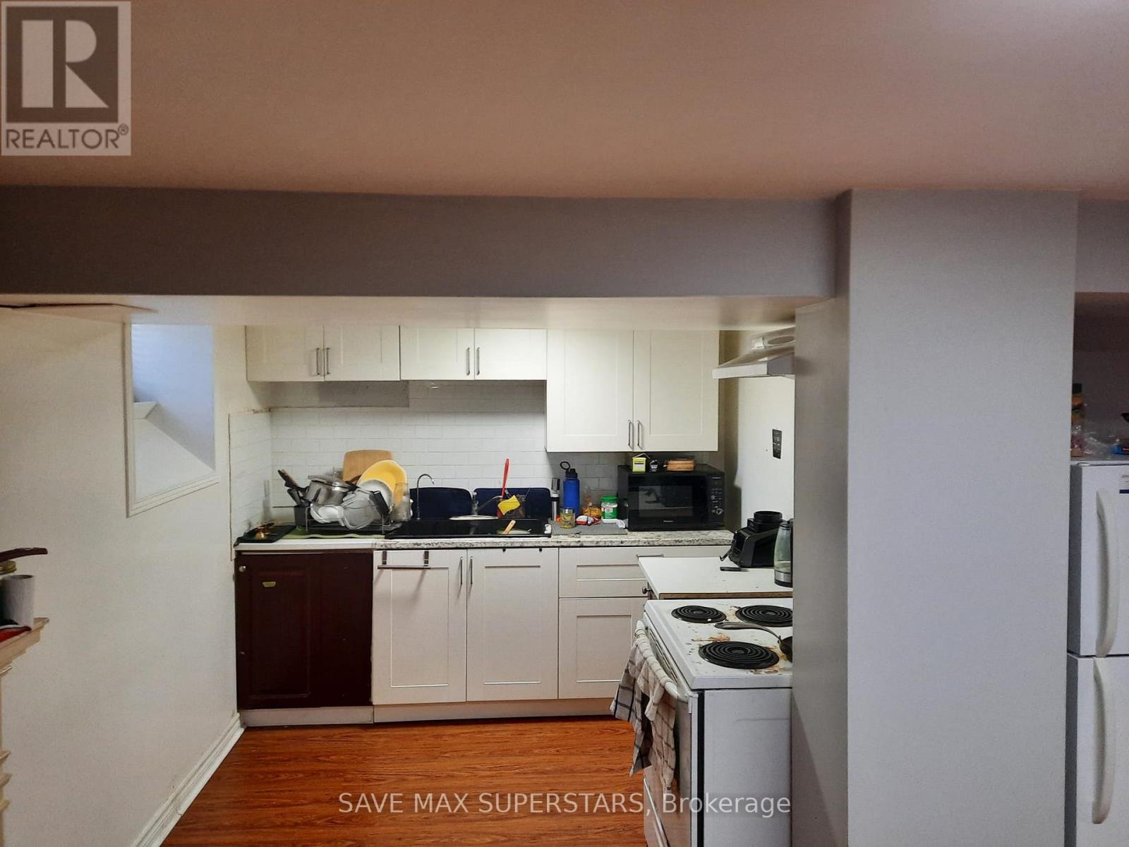 A kitchen with white appliances and wooden floors.