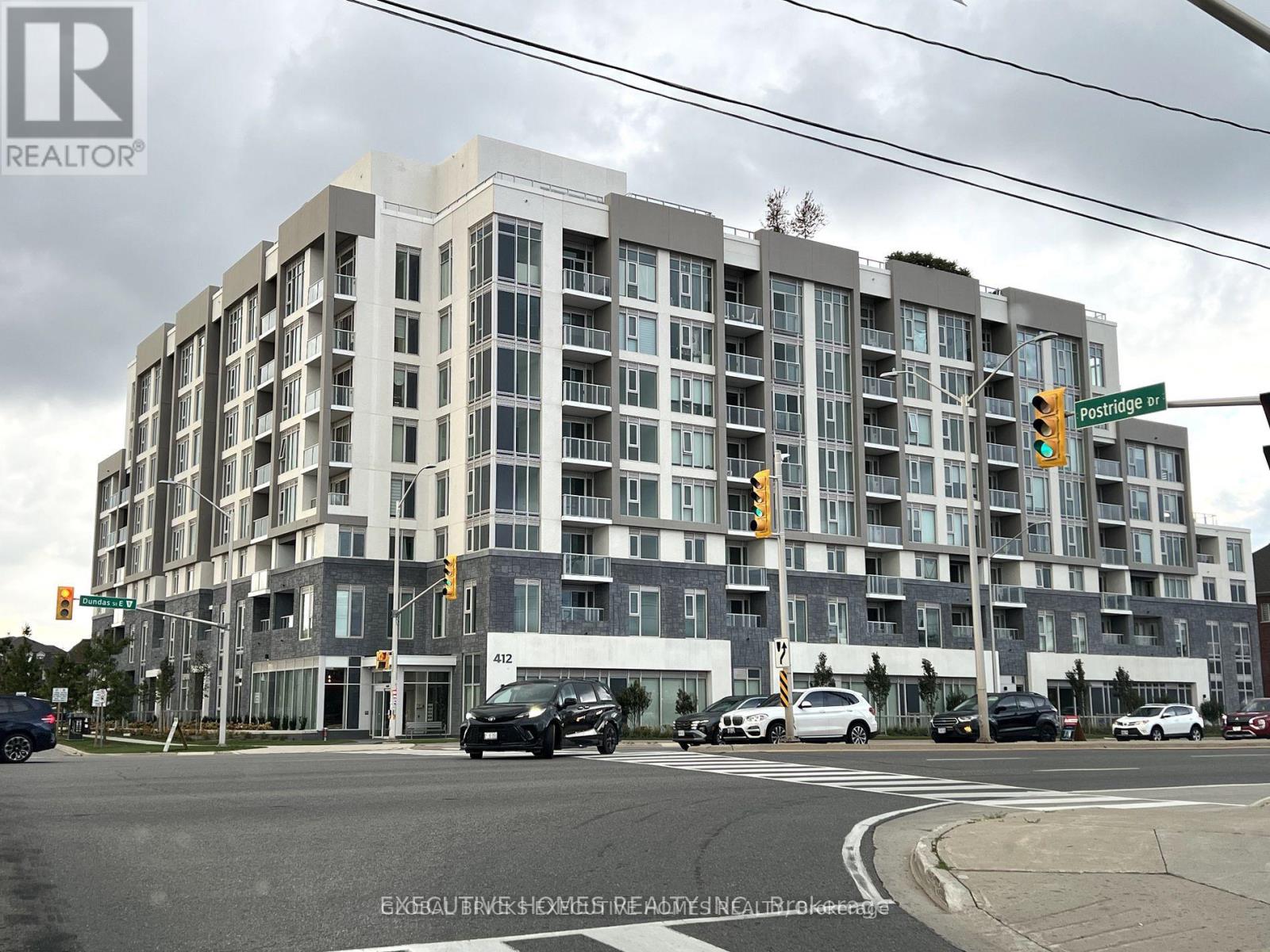 A multi-story building with a grey facade and a sign that reads "REALTOR" on the top left corner.