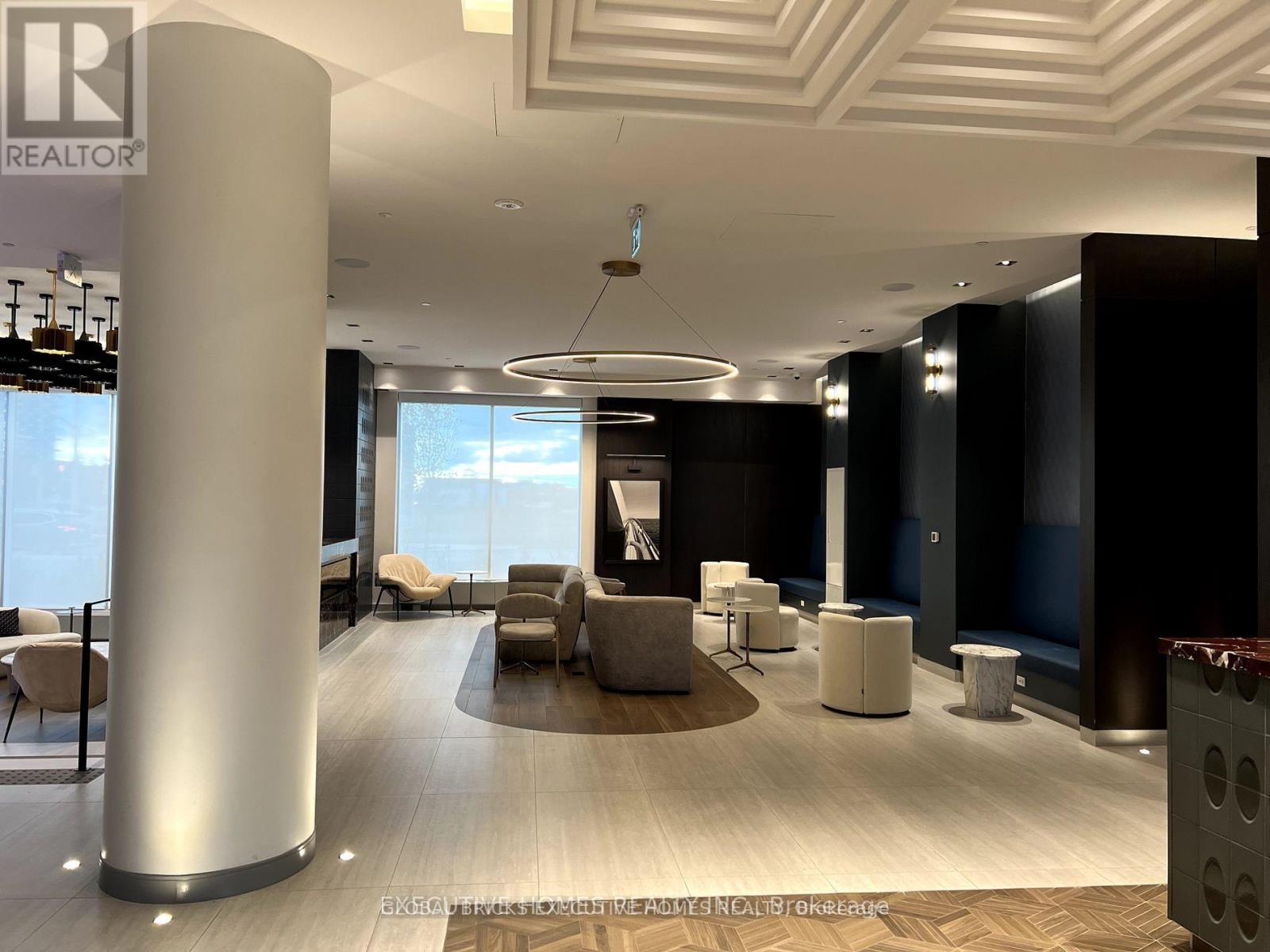 A modern office lobby with a large column and a view of the sky through the windows.