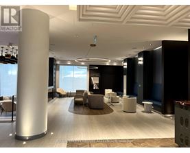 A modern office lobby with a large column and a view of the sky through the windows.