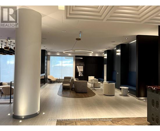 A modern office lobby with a large column and a view of the sky through the windows.
