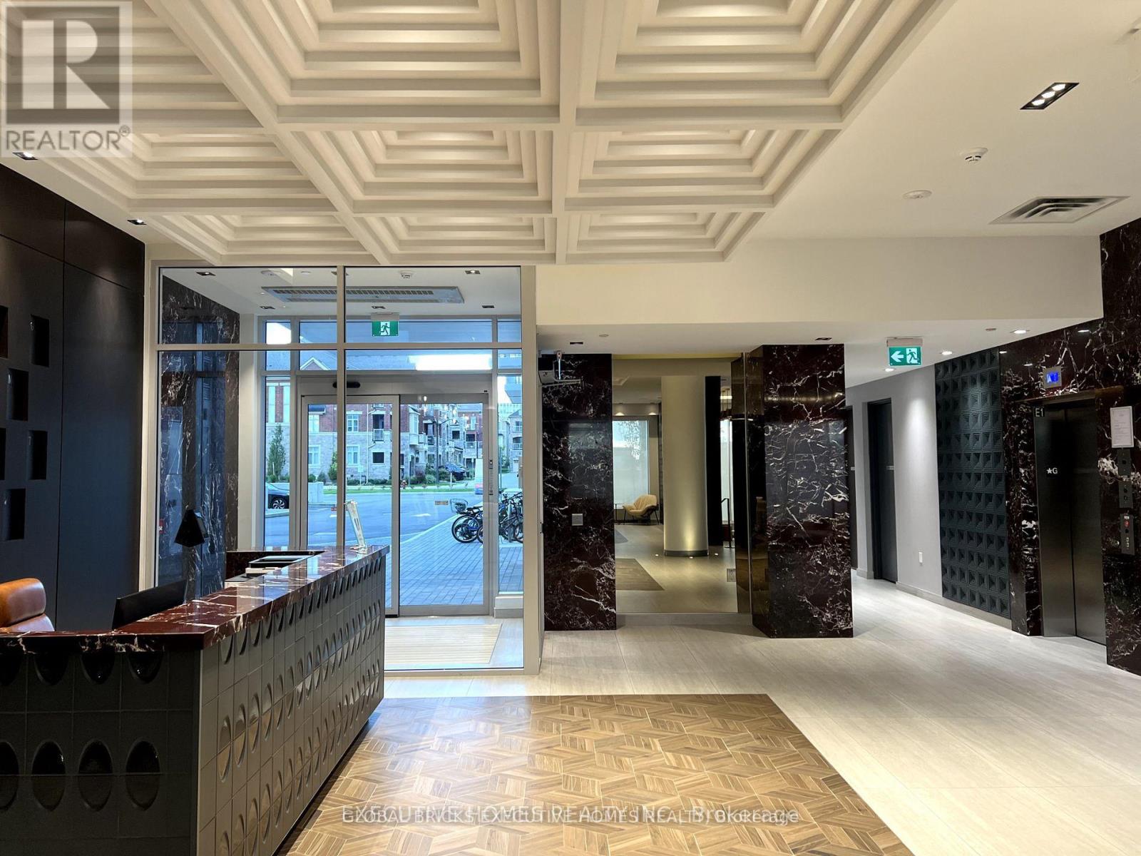 The image shows a well-lit, modern office lobby with a reception desk and a marble floor.