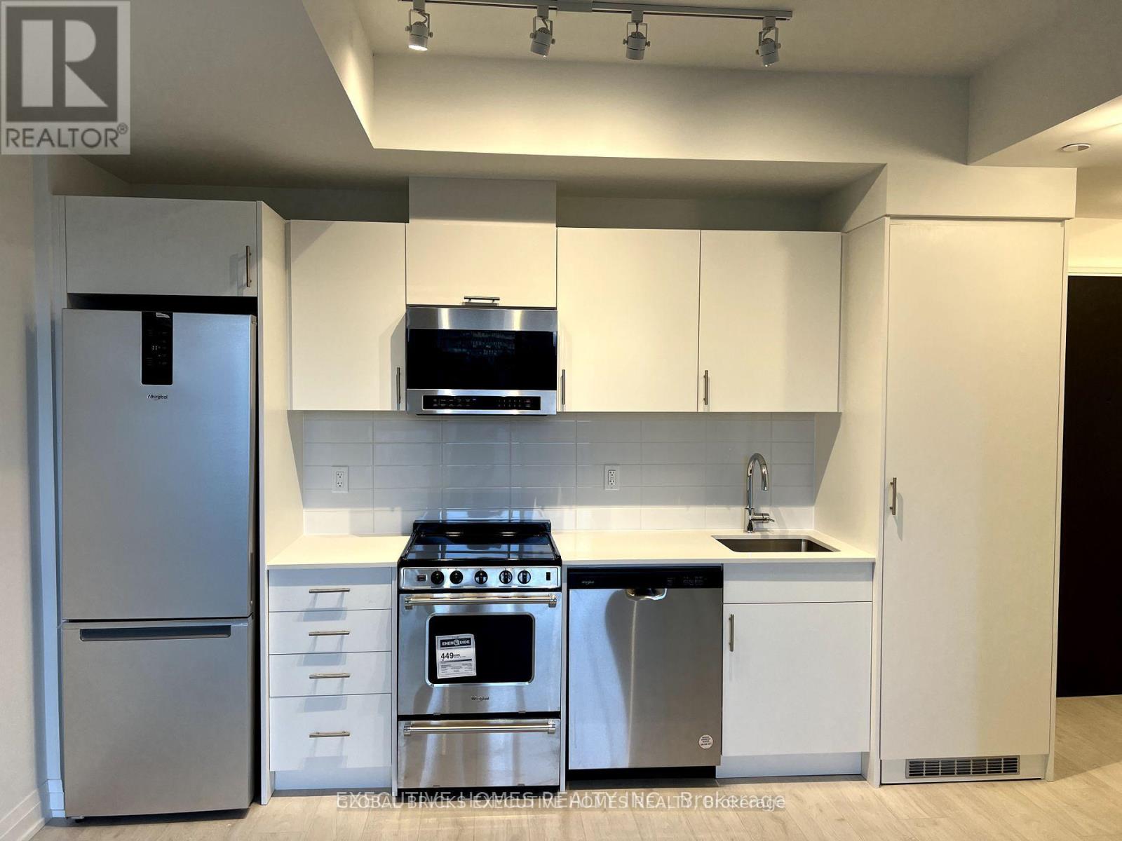 A modern kitchen with white cabinets and stainless steel appliances.