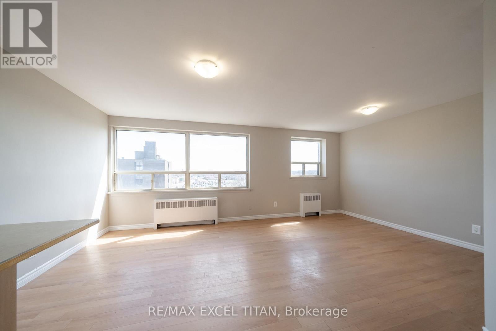 A spacious room with wooden floors and large windows.