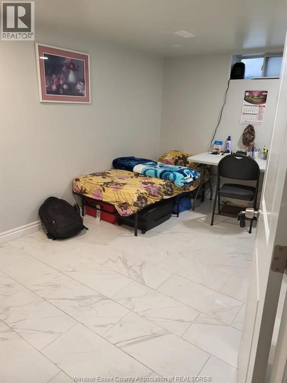 A bedroom with a bed, desk, chair, and a backpack.
