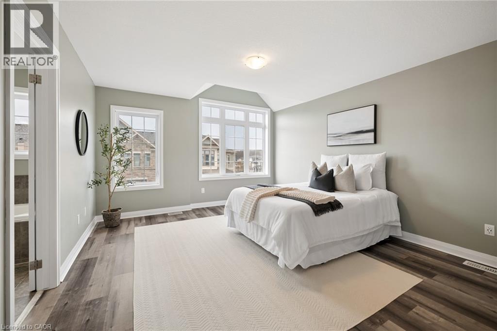 A bedroom with a large bed and a window overlooking a neighborhood.