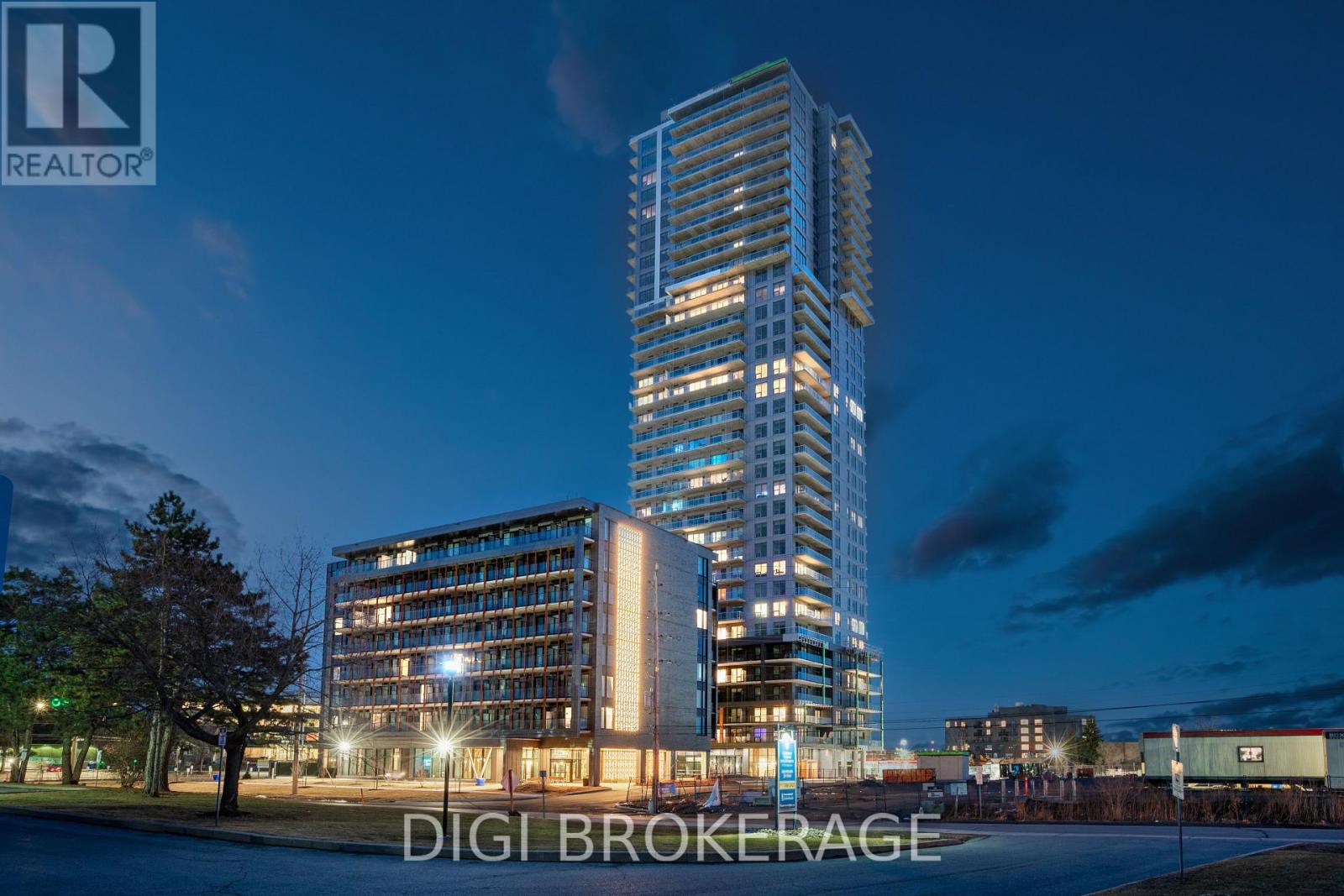 A tall building with the words DIGI BROKERAGE on it is lit up at night.