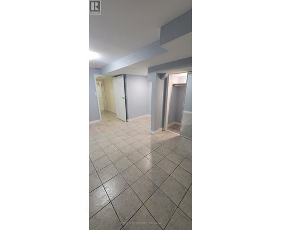 A spacious room with tile flooring and white walls.