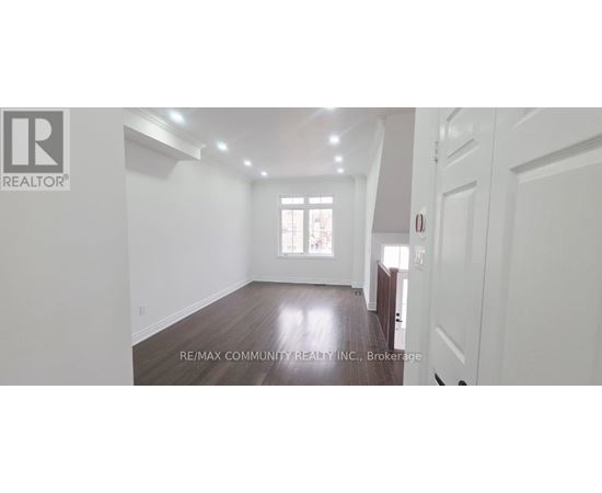 A spacious room with wooden floors and white walls.