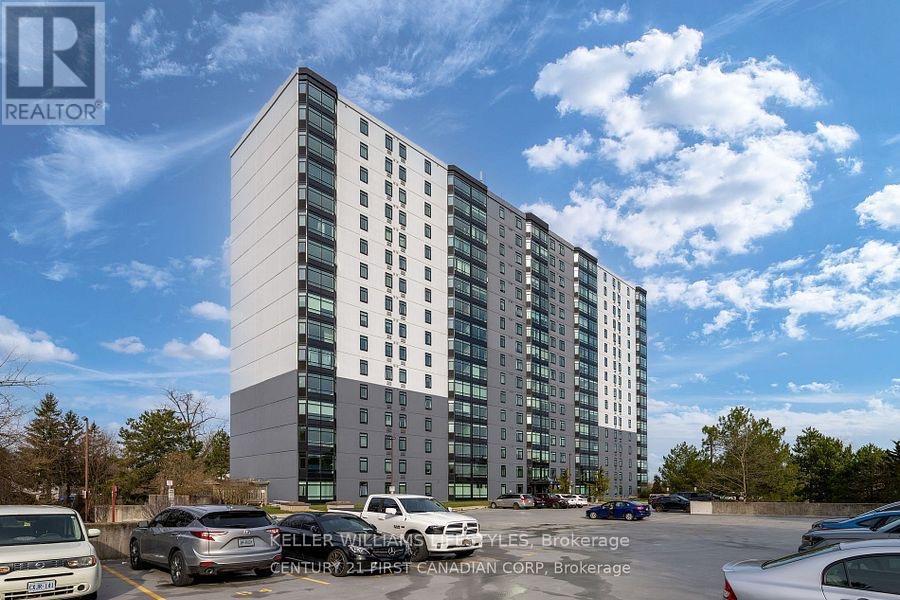 A modern multi-story building with a parking lot in front.