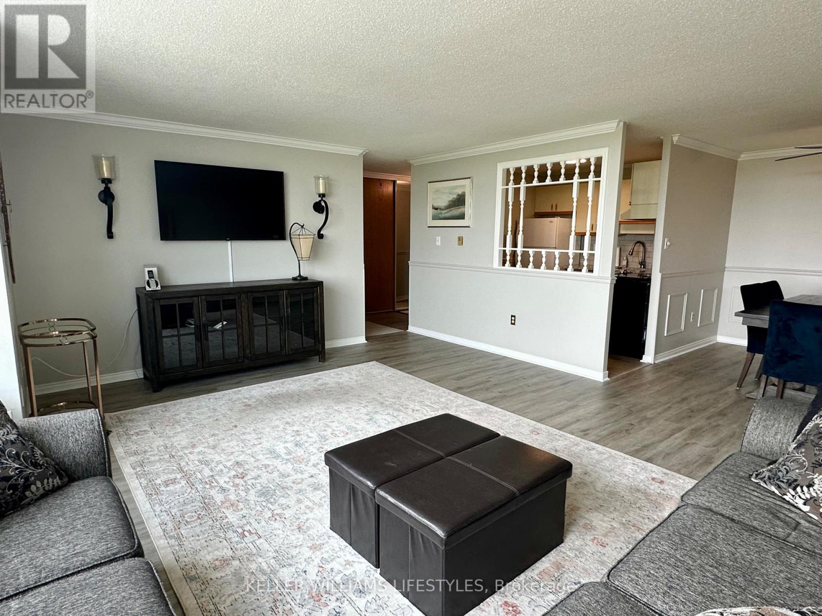 A living room with a grey sofa, a black coffee table, and a television mounted on the wall.