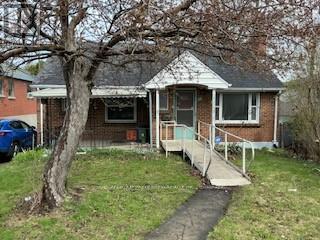 A small house with a porch and a tree in front.