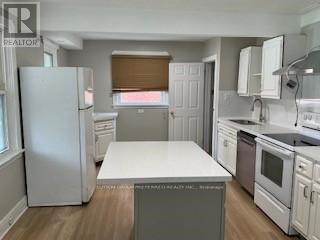 A kitchen with white appliances and a white island.