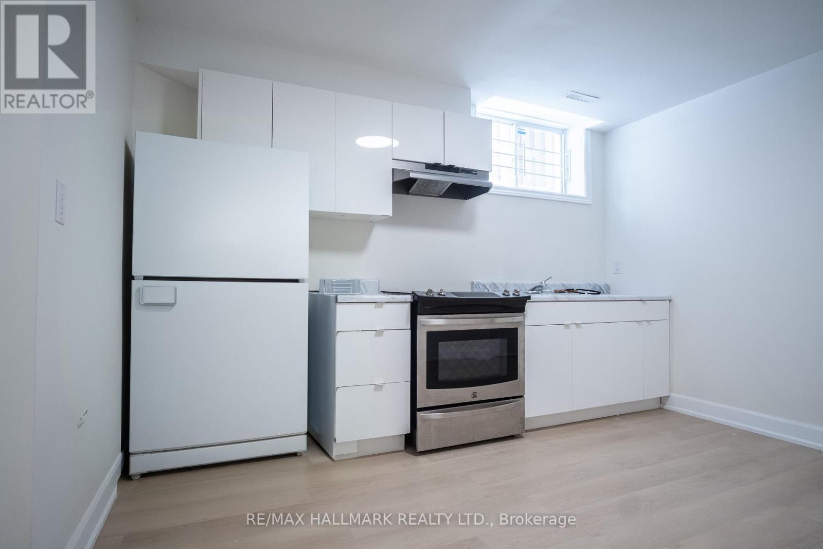 A white kitchen with a fridge, oven, and microwave.