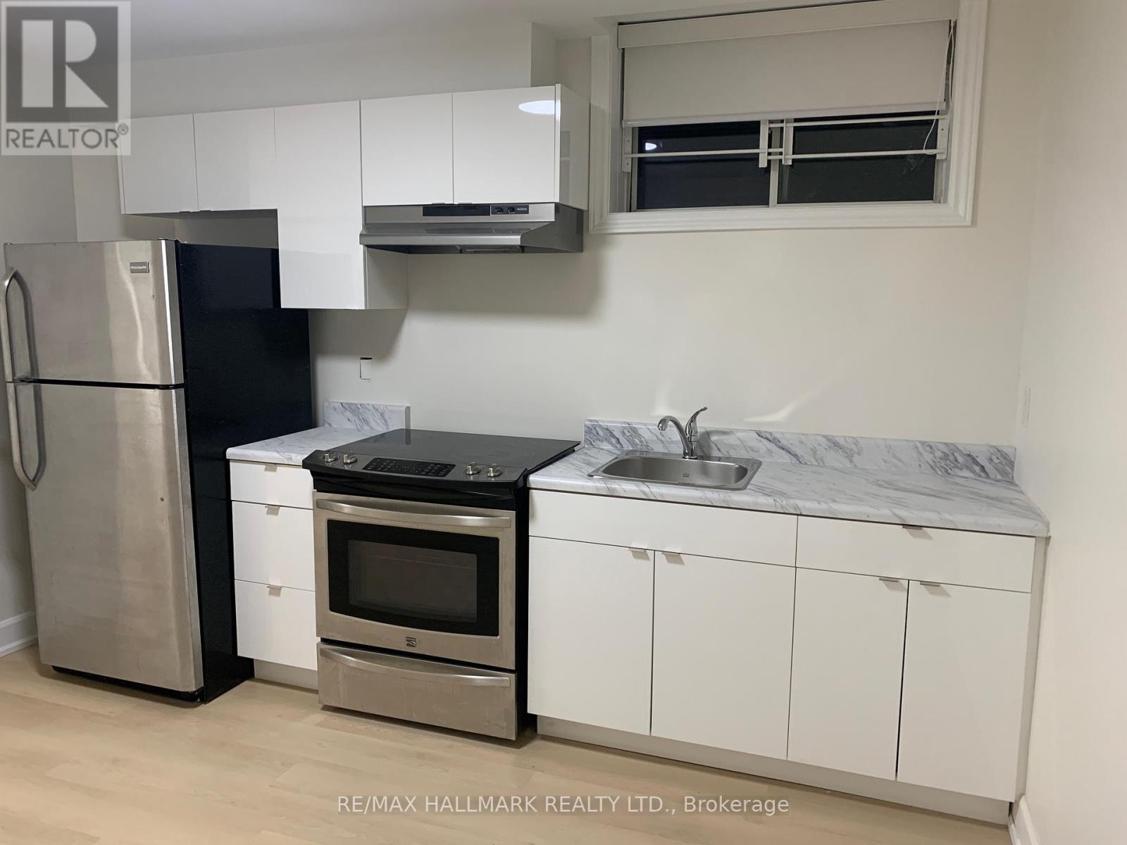A kitchen with white cabinets and a black fridge.