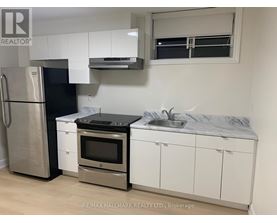 A kitchen with white cabinets and a black fridge.