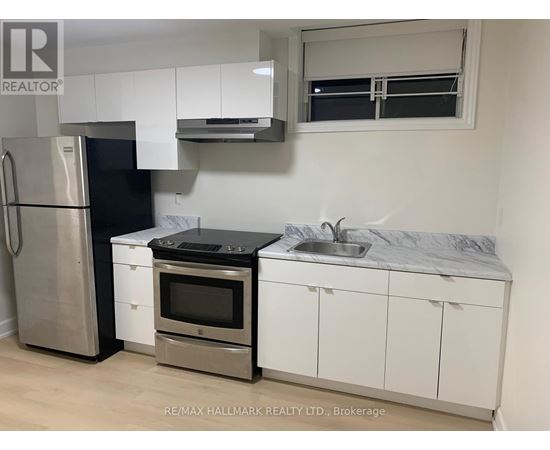 A kitchen with white cabinets and a black fridge.