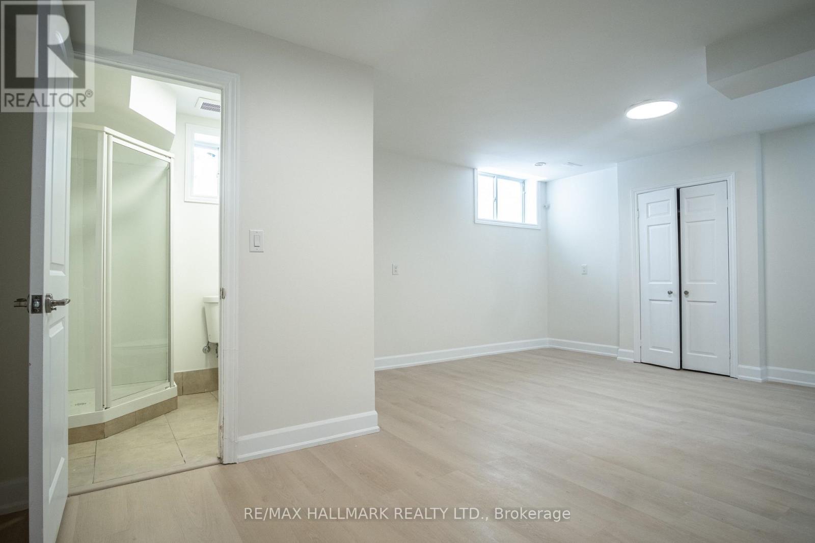 A spacious room with a door, a window, and a glass door leading to a balcony.