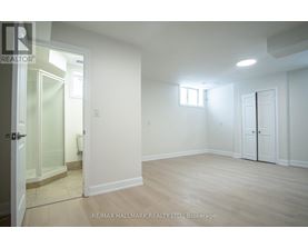 A spacious room with a door, a window, and a glass door leading to a balcony.