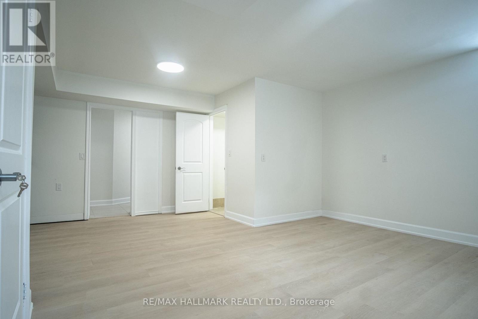 A white room with wooden floors and a door on the left.