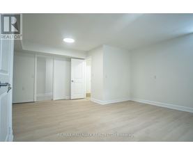 A white room with wooden floors and a door on the left.