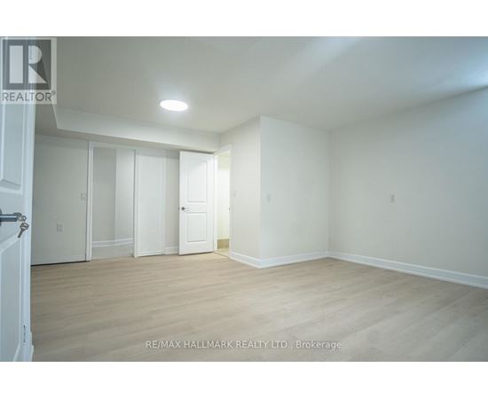 A white room with wooden floors and a door on the left.
