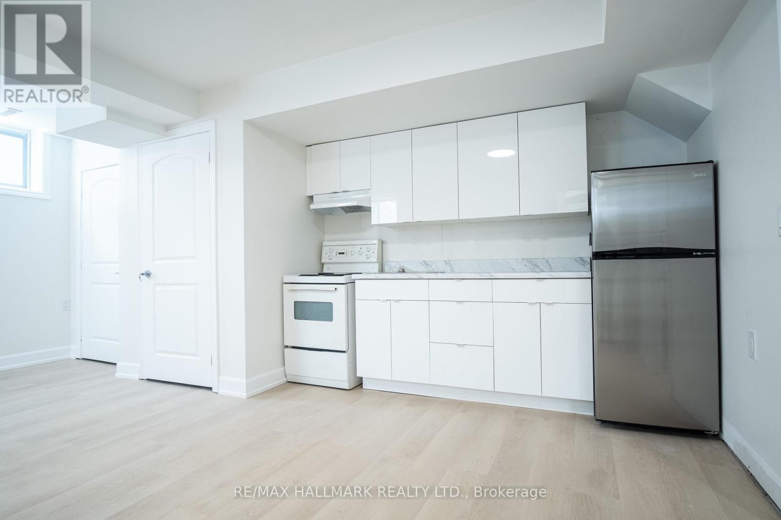 A kitchen with white cabinets and appliances in a room with wooden floors.
