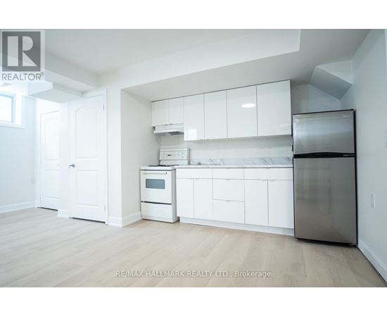 A kitchen with white cabinets and appliances in a room with wooden floors.