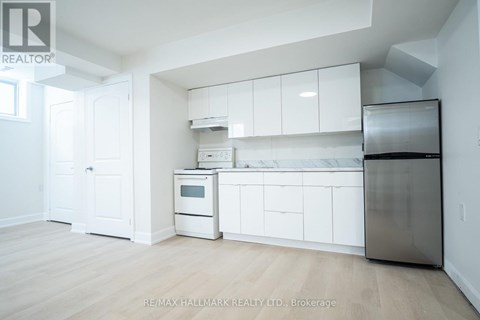 A kitchen with white cabinets and appliances in a room with wooden floors.