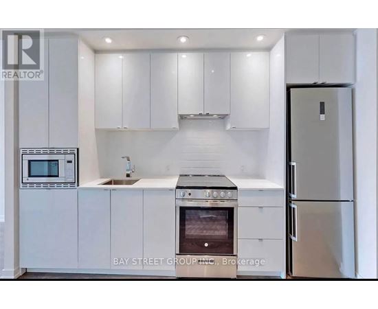 A modern kitchen with white cabinets and appliances.