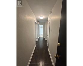 A hallway with a black door and white walls.