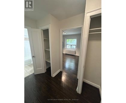 A room with white walls and dark wood floors.