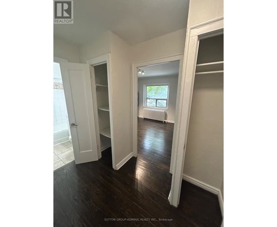 A room with white walls and dark wood floors.